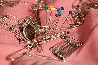 Sewing Thimble, Safety Pins, and Colorful Pins on Pink Fabric