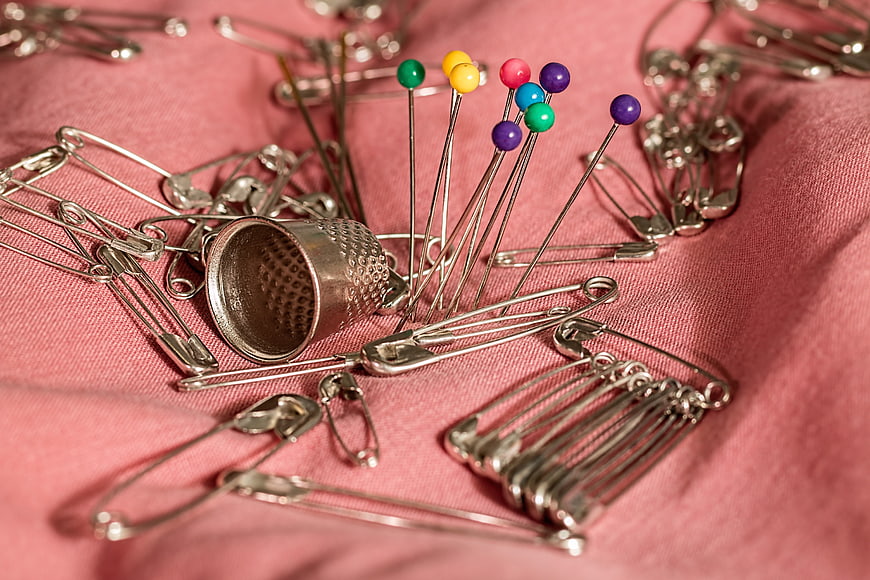 Sewing Thimble, Safety Pins, and Colorful Pins on Pink Fabric