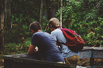 Two male hikers resting on wooden railing in forest