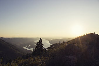 Sunset Over Winding River Valley and Forested Hills