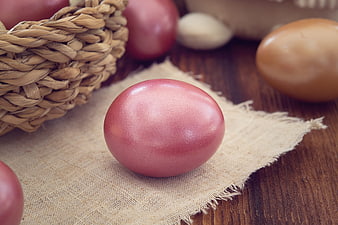 Close-up of pink Easter egg on burlap with basket
