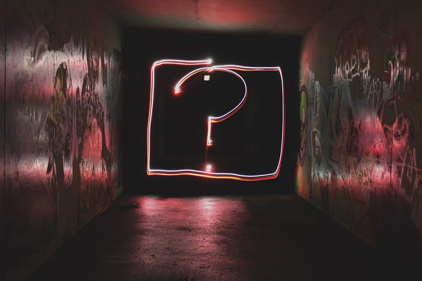 Neon light painting question mark in graffiti tunnel