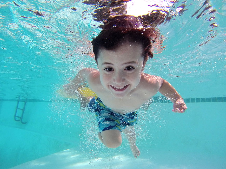 Happy Boy Swimming Underwater in Pool