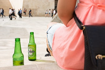 Heineken beer bottles on stone ledge with woman in pink