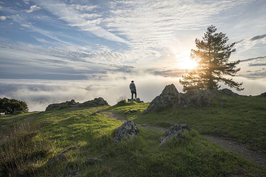 Lone Hiker on Mountain Summit Above Sea of Clouds at Sunrise