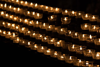 Rows of lit tea light candles in a dark church setting