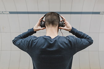 Man from behind wearing headphones in subway station