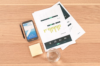 Flat lay of business documents, smartphone, and office supplies on wooden desk