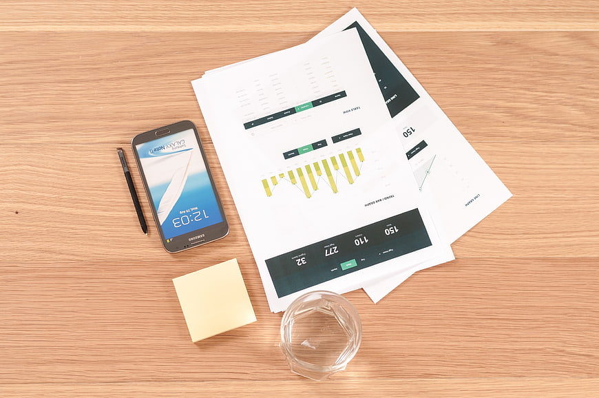 Flat lay of business documents, smartphone, and office supplies on wooden desk