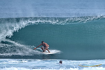 Surfer riding a large turquoise wave barrel