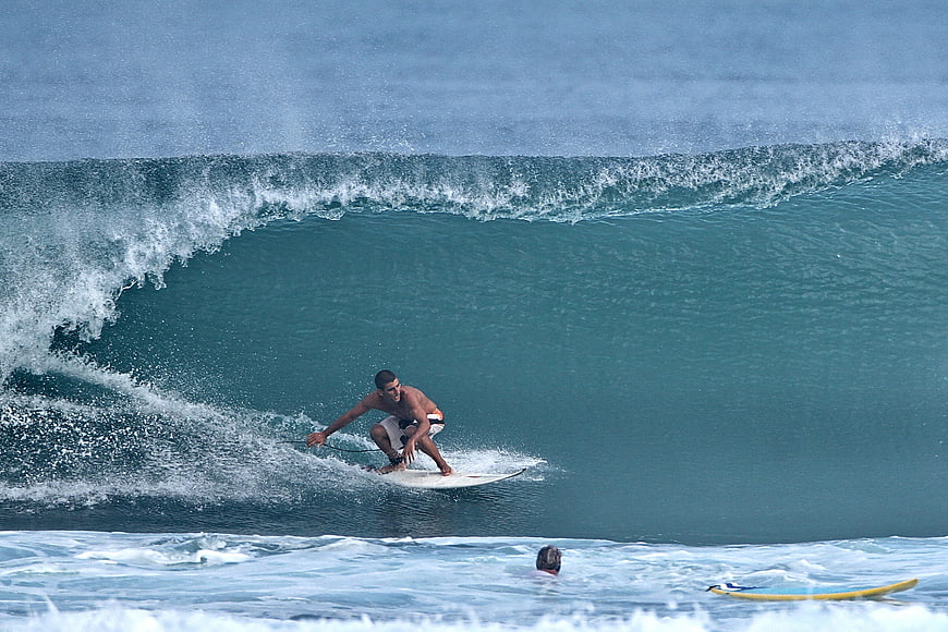 Surfer riding a large turquoise wave barrel