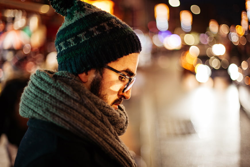 Man in Beanie and Scarf Looking Down at Night