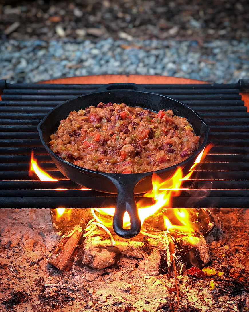Cast Iron Skillet of Chili Cooking Over Campfire