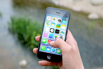 Hand holding smartphone with app icons on screen