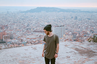 Young man with beanie overlooking Barcelona cityscape from Tibidabo