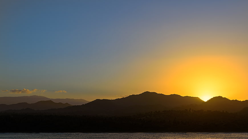 Golden Sunset Over Silhouetted Mountain Range and Water
