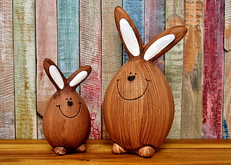 Two Cute Wooden Easter Bunny Figurines on Rustic Shelf