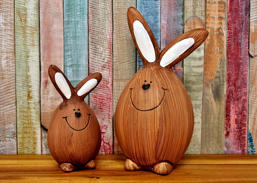 Two Cute Wooden Easter Bunny Figurines on Rustic Shelf