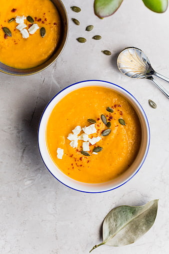 Overhead view of creamy orange pumpkin soup with seeds and cheese