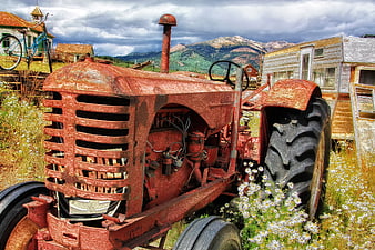 Rusty vintage red tractor in rural mountain landscape