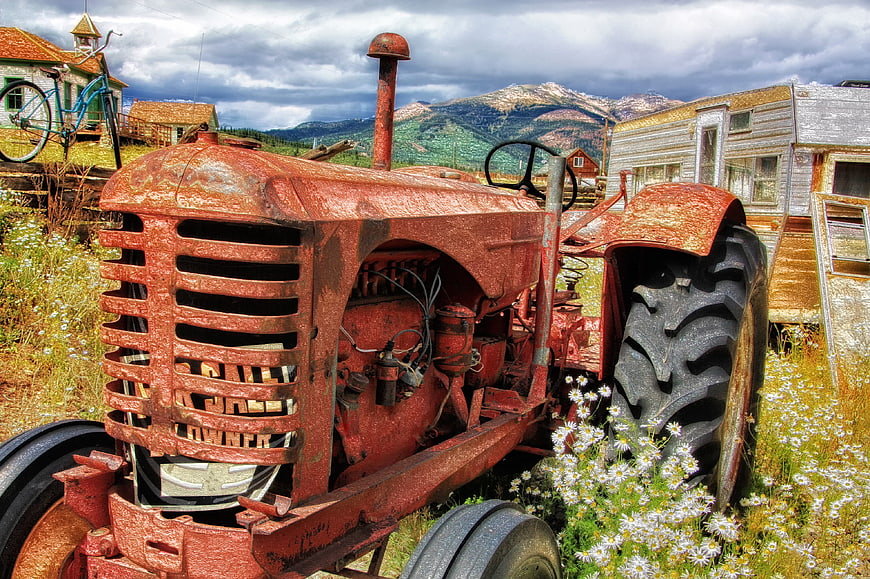 Rusty vintage red tractor in rural mountain landscape
