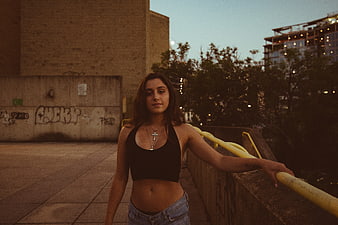 Young woman leaning on railing in urban setting at dusk