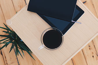 Flat lay of coffee, tablet, and notebook on wooden tray