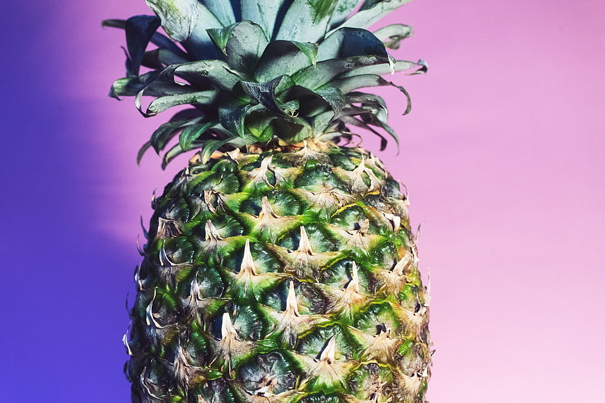 Close-up of a pineapple on a purple and pink gradient background