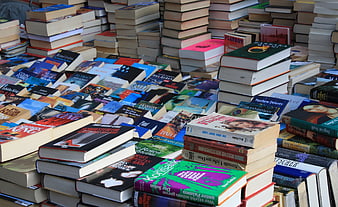Stacks of colorful used books at an outdoor flea market