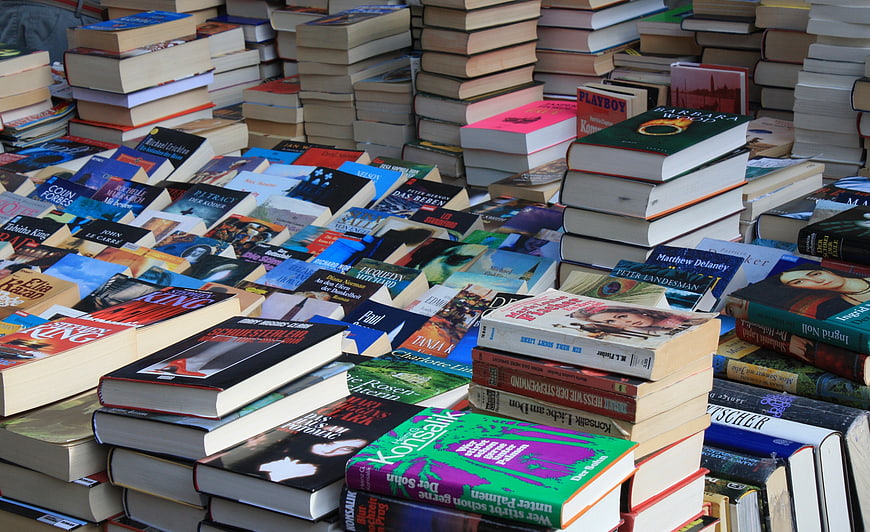 Stacks of colorful used books at an outdoor flea market