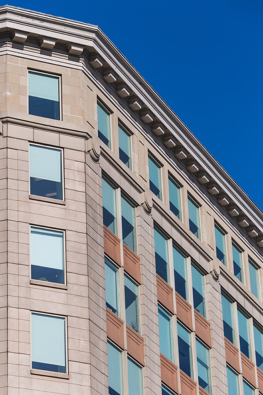 Low angle view of modern beige building facade against blue sky
