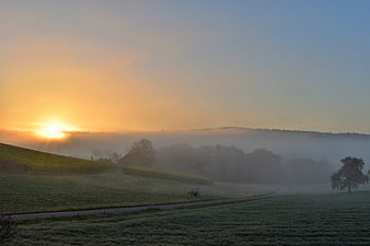 Misty Sunrise Over Rolling Green Hills and Foggy Valley