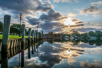 Dramatic sunrise over calm river with wooden dock and reflections