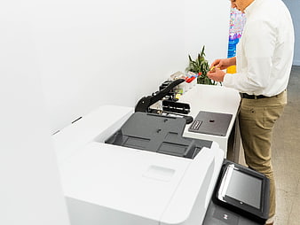 Man working at office desk with printer and laptop