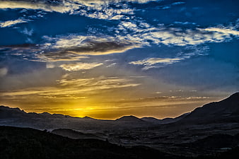 Dramatic sunset over mountain range with golden clouds