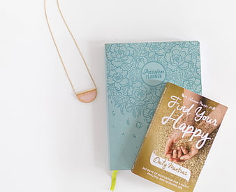 Flat lay of self-help books and gold necklace on white background