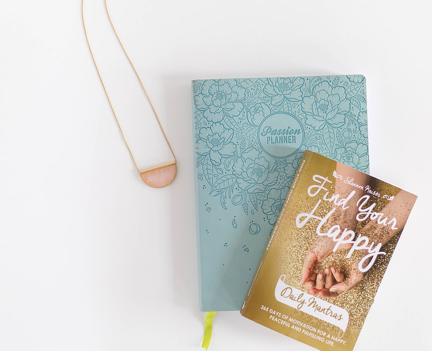 Flat lay of self-help books and gold necklace on white background