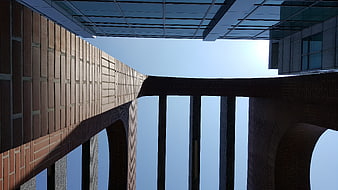 Low angle view of modern brick and glass architecture against blue sky
