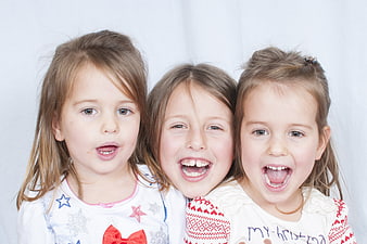 Three happy young girls smiling and laughing together in a studio portrait