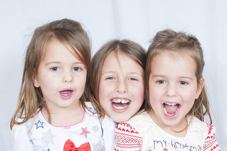 Three happy young girls smiling and laughing together in a studio portrait