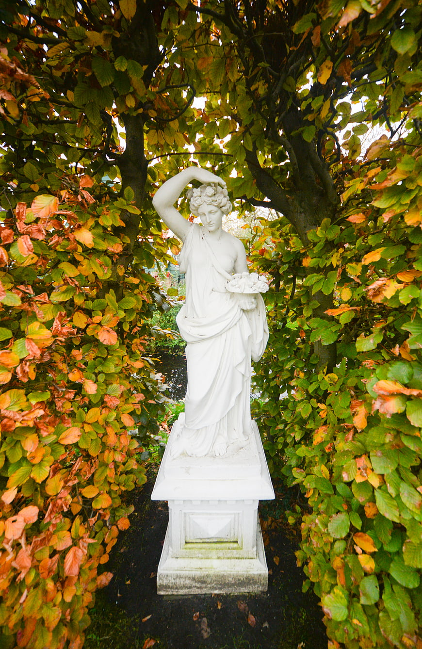 White Classical Statue in Autumn Garden Archway