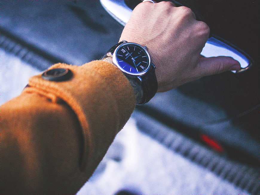 Man's wrist with watch opening car door handle