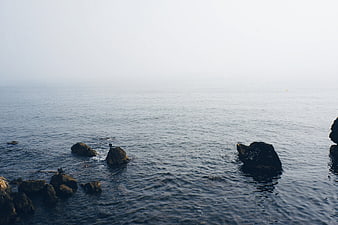 Serene Ocean View with Rocks and Misty Horizon