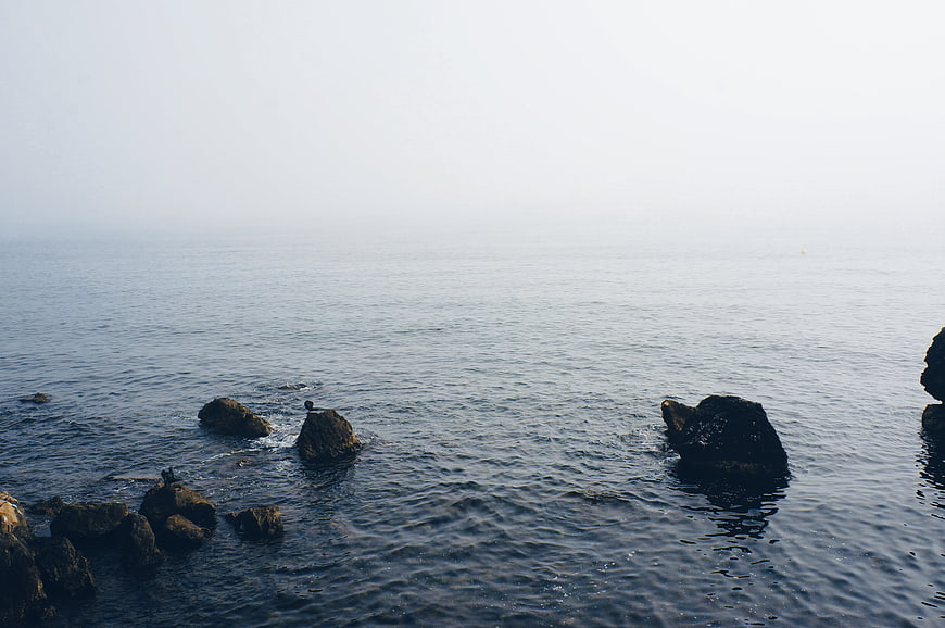 Serene Ocean View with Rocks and Misty Horizon