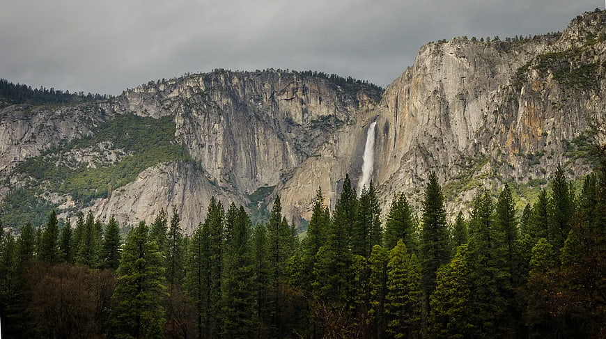 Majestic waterfall cascading down granite cliffs in a forest