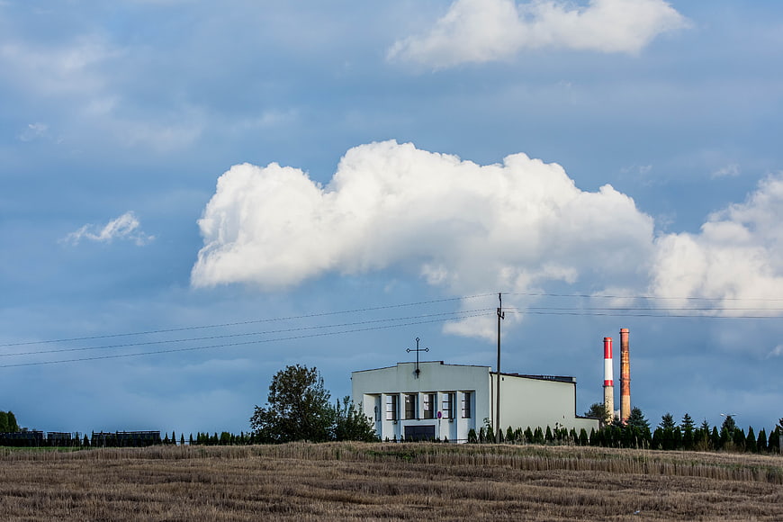 White Church with Cross and Industrial Chimneys in Rural Landscape