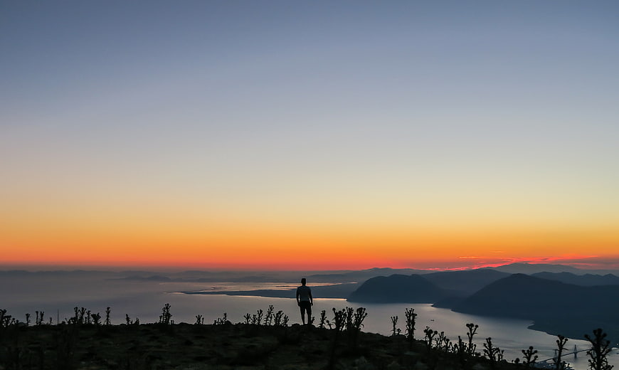 Silhouette of man overlooking lake at sunset