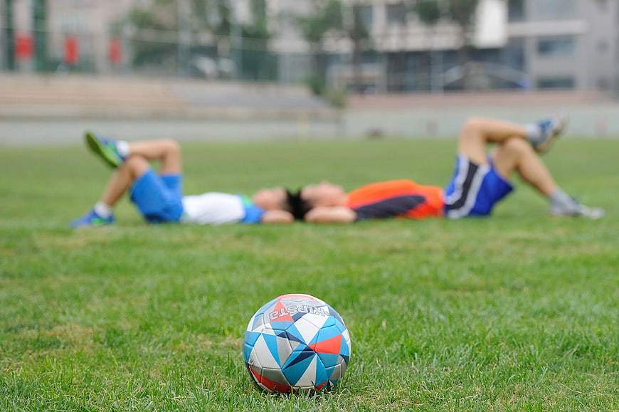 Soccer ball on grass with resting players in background
