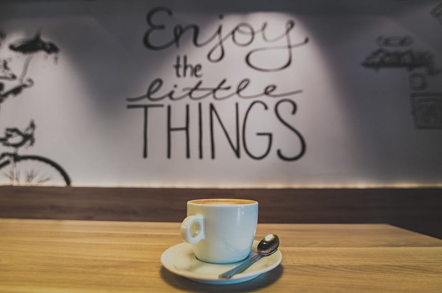 White Coffee Cup on Wooden Table with Inspirational Wall Text