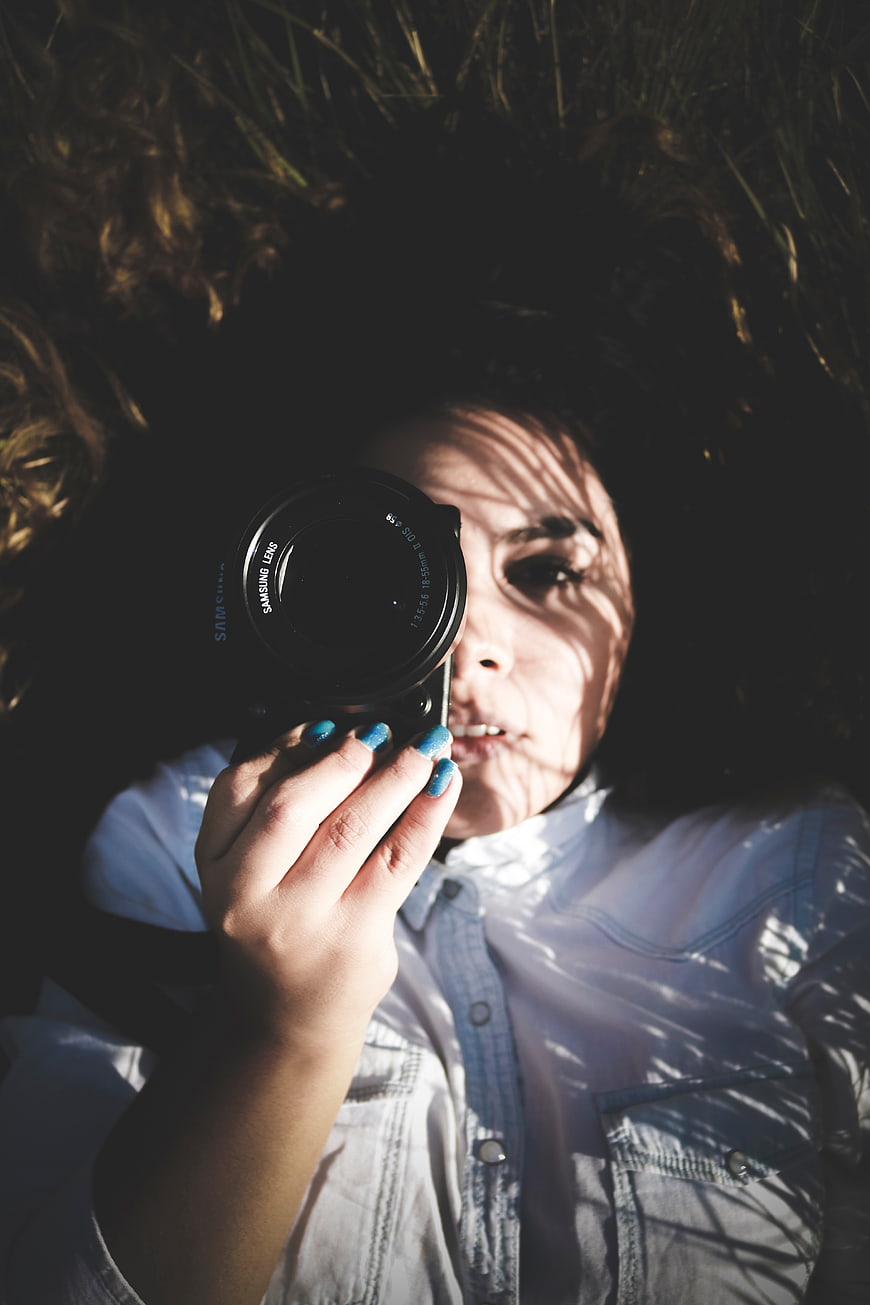Woman Photographer Lying in Grass with Camera